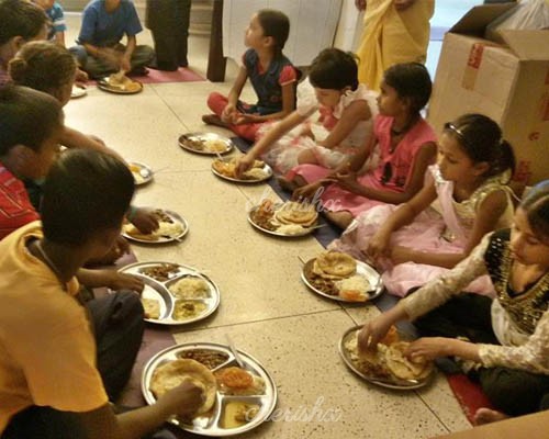 Children having food sitting in alignment at the orphanage.
