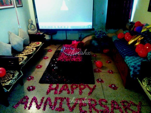 A room decorated with rose petals and a projector installed for the surprise.