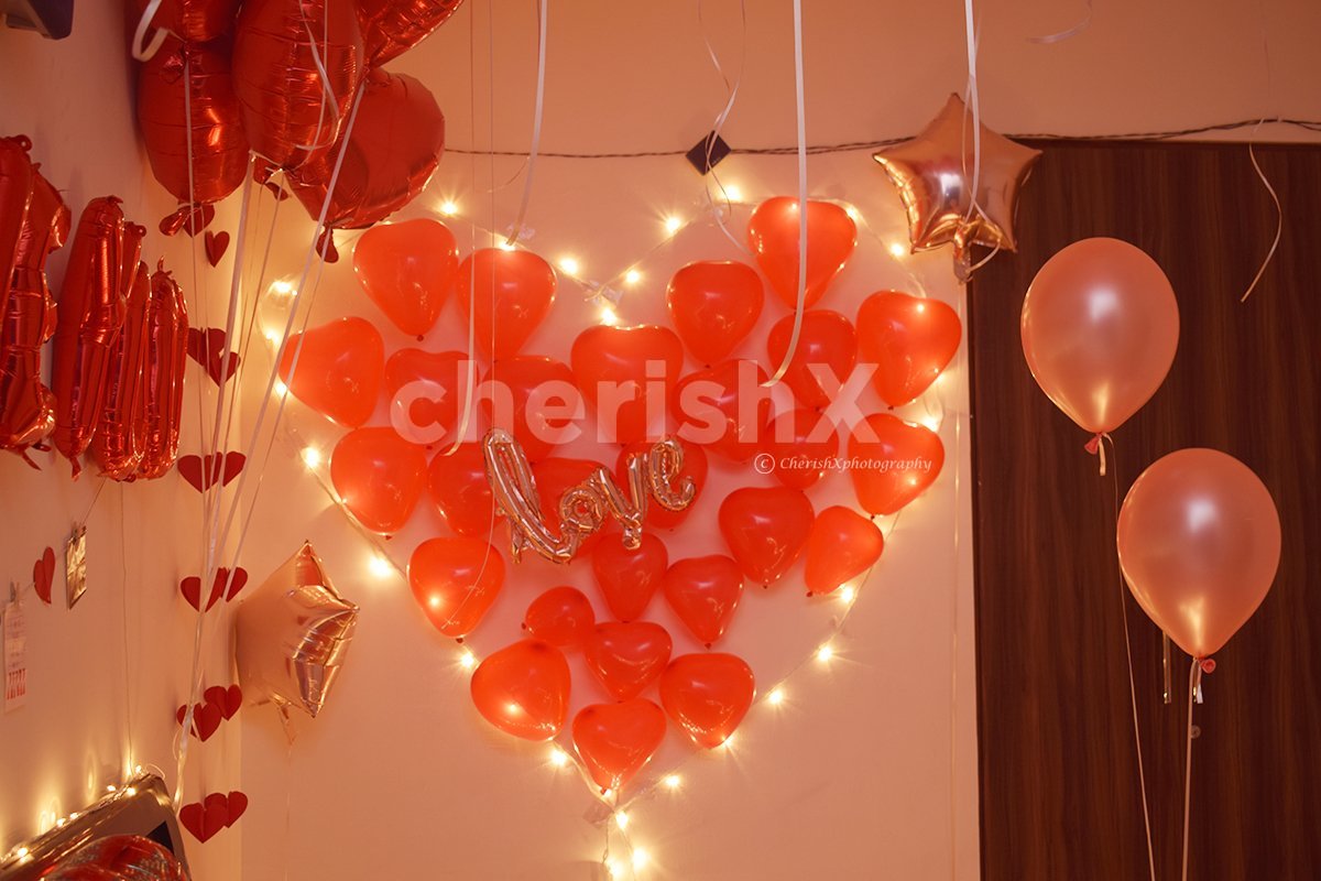 A heart made up of lights and red-coloured balloons for the room decoration.