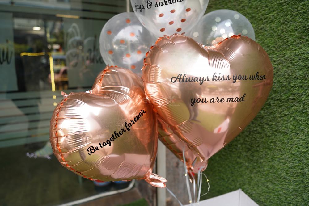 Two heart-shaped rose gold foil balloons with 1 promise on each.