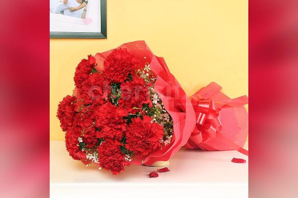 A bouquet of 10 red carnations wrapped in red paper.