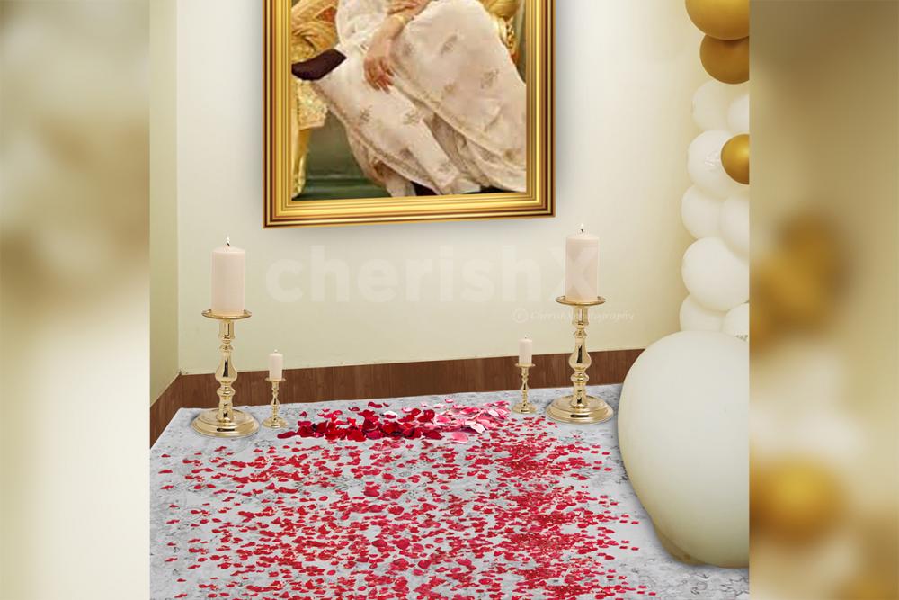 CherishX's Guruji Birthday Decor includes Rose petals and candles spread out on the floor.
