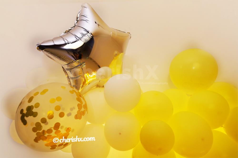 The arc of balloons is made with white,  pastel yellow, yellow latex balloons.