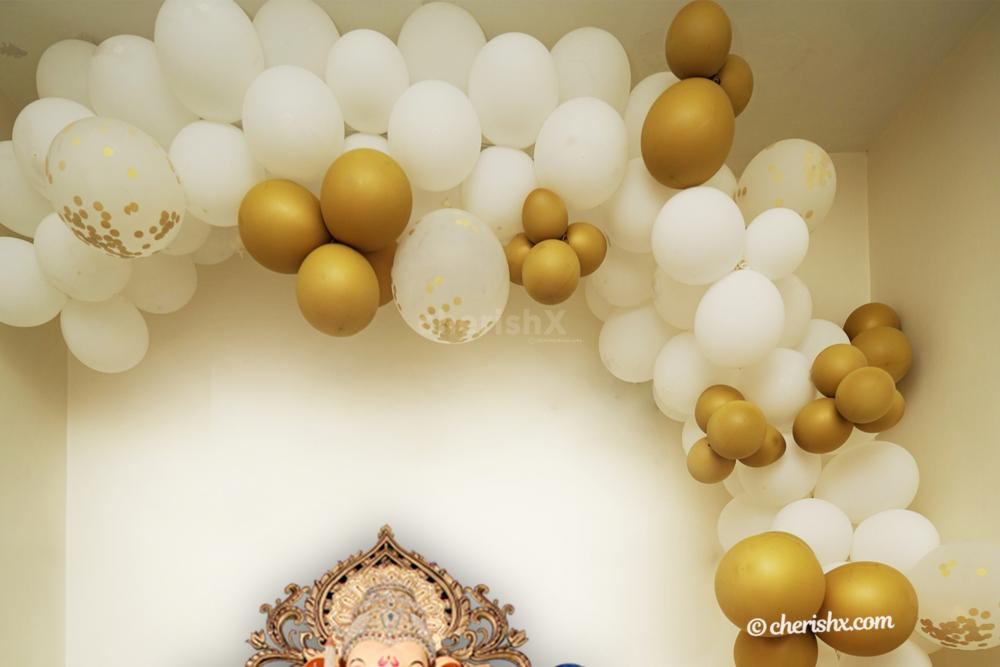 An arch made of white and golden balloons, giving the decor a brighter look.
