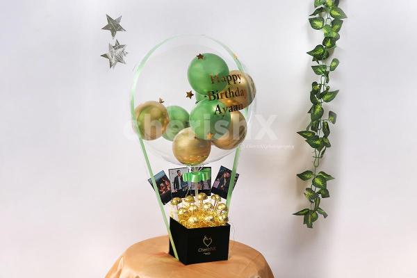 CherishX's Gold & Green Balloon Bucket with Chocolates is designed to bring joy to the face of the recipient!