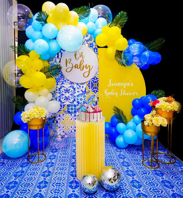 Picture-perfect moments await amidst a backdrop of sun board cutouts, a captivating 'Oh Baby' centrepiece, and a burst of yellow, white, and blue balloons.