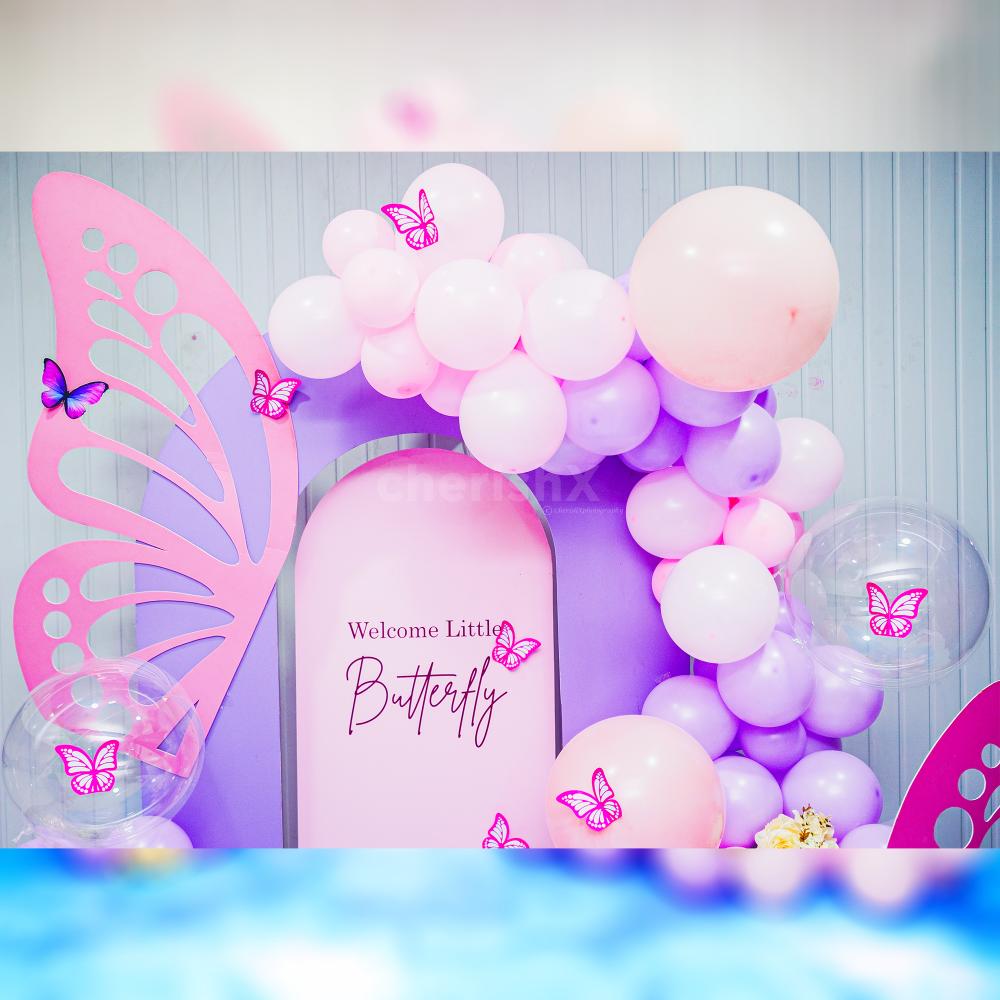 The decor features graceful butterfly cutouts and a delightful blend of purple and pink balloons.