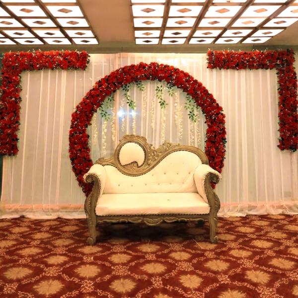 A stunning peach cloth backdrop adorned with natural red roses and leaves creates a captivating and romantic ambiance.