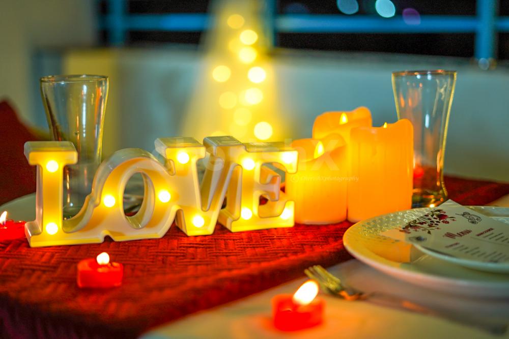 Candles and creative menus adorn the dinner table, setting the mood for an intimate and romantic dining affair.