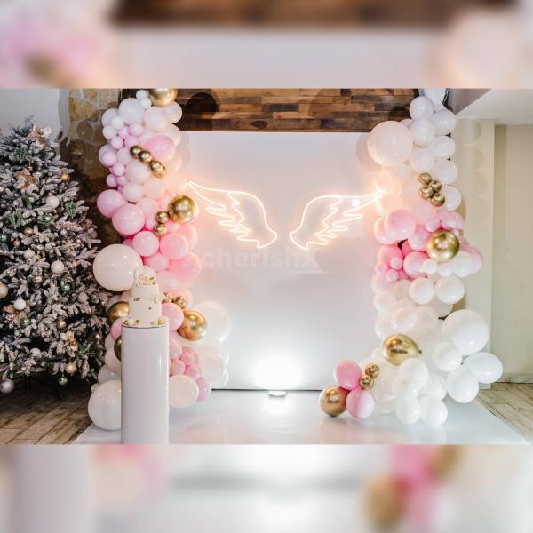 Immerse yourself in the enchantment of the Blissful Feather Fantasy baby shower decor featuring a dreamy setting with delicate pink balloon garlands, creating a joyful and celebratory atmosphere.
