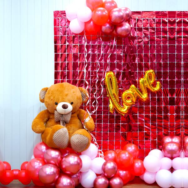 The decor is accompanied by a shiny foil curtain and a teddy bear.
