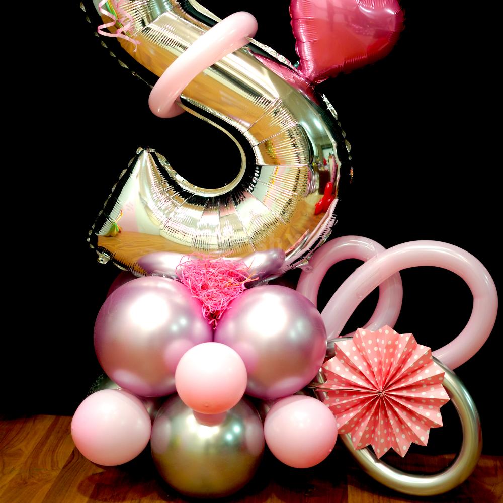 The balloon bouquet is complemented by pretty pink rosettes, pink grass, and an assortment of pink and silver chrome BT balloons.